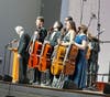 Maestro Drostan Hall taking bows with five young cellists who performed with Camerata Chicago that evening.