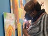 Valerie Frink of Jersey City, a VLANJ participant, closely inspects a bright, colorful work by artist Jerry Pinkney, using the flashlight on her mobile phone.