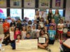 Carol Reeks (bottom right) and her class pose with a check and plaque presented by (top L to R) Megan Johnson, Sharon Daly, Brandy Cafarelli, and Stacie McGlone.