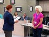 District 146 Board President Darcy Nendza (left) reads a resolution adding Laura Bachman (right) to the Wall of Fame.
