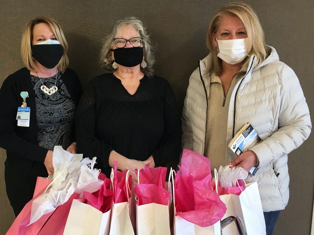 Franciscan Health Foundation Executive Director Laurie Crosby, left, accepts a donation of prayer shawls and hats for cancer patients from Jennifer Wilkins, center, and Mary Beth Bohadlo.