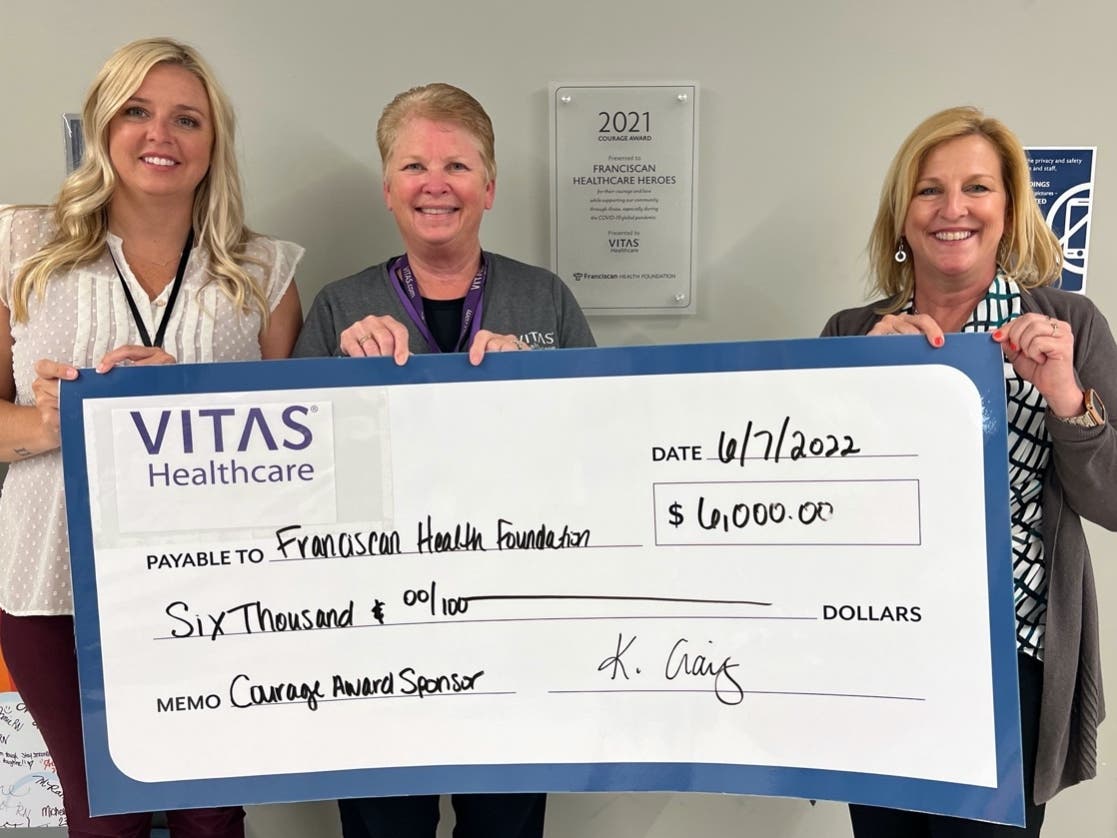 VITAS Healthcare director of market development Karianne Craig (left) and VITAS senior account representative, Margaret Sheets present the 2022 Courage Award sponsorship to Laurie Crosby, Franciscan Health Foundation executive director.