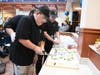 Michael Boughman (foreground) and Devon Riggs serve up a beautifully decorated cake, donated by Aversa Bakery, at the Together Café’s official grand opening party on Nov. 15.