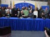 Dr. Frederick Keating (center-right) shakes hands with Robert Bumpus as they and representatives from 24 area high schools sign into place the RCSJ Collegiate High School program.