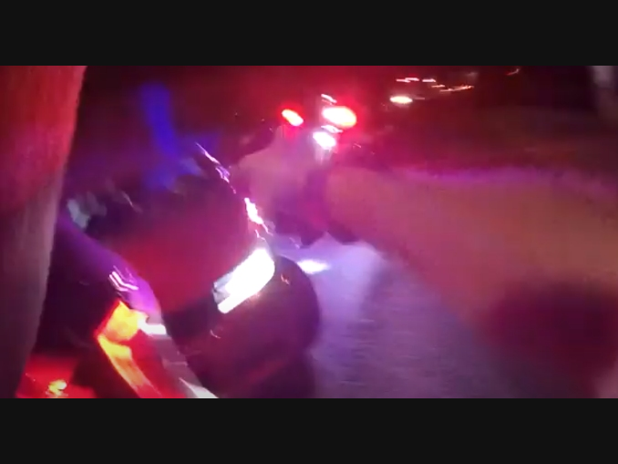 A still image from body camera footage that shows an officer firing shots at a charging car during a traffic stop in Naugatuck.