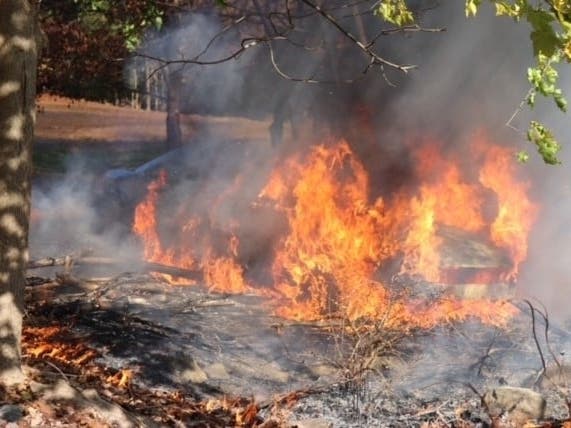 A fire department safety officer pulled an unconscious person from a burning car, according to officials.