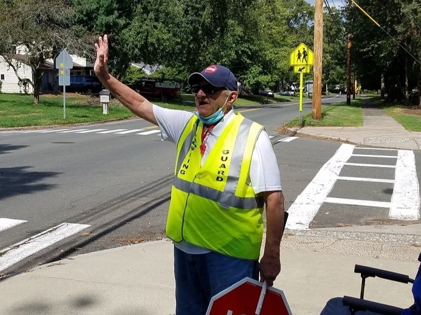 Jim Snedeker waves to drivers outside of Dag Hammarskjold Middle School in Wallingford at the beginning of the school year. Snedeker announced that Friday was his last day at his beloved post.