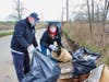 Public Works Commissioner Tom J. McCarthy holds a trash bag while Mayor Nancy R. Rossi disposes of a plastic bucket found in a marsh off Spring Street during the city’s Earth Day cleanup Thursday.