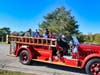 Children and parents ride in a 1935 Mack pump firetruck driven by retired West Haven Fire Department Inspector Robert Abate. The firetruck was formerly operated by the department’s North End Hose Company.