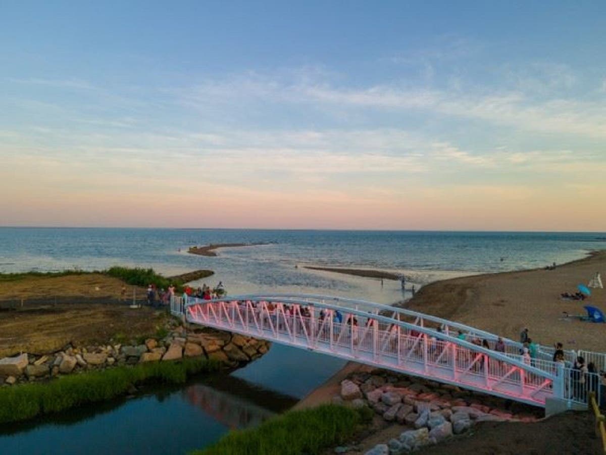 People walk across West Haven’s new Cove River pedestrian bridge, illuminated with red-and-white LED lights, for the first time in more than 20 years during a “light the bridge” celebration to mark its official opening Tuesday evening, July 19.