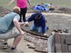 Scouts and other volunteers lay the bricks that make up the outer ring of the garden.