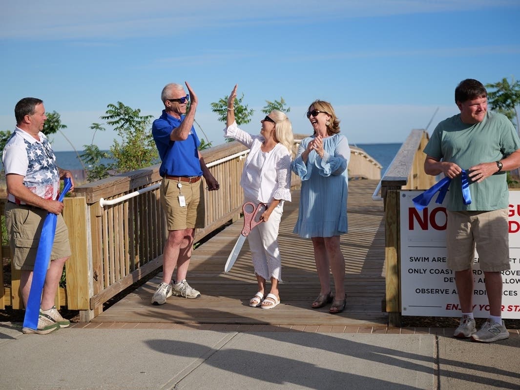Land Trust of West Haven President Marilyn Wilkes, holding scissors, gives city Parks and Recreation Director Mark E. Paine Jr. a high-five after cutting the ribbon with Mayor Dorinda Borer on Tuesday, June 16, to celebrate the grand opening of Eco Park.