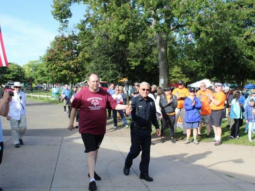 West Haven Police Chief Joseph S. Perno helps torchbearer Sean DelGreco of the Team North Haven bocce team carry in the “flame of hope.”