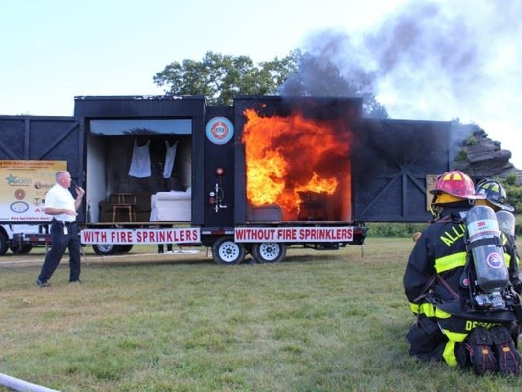 City of West Haven Fire Department Allingtown Deputy Chief Keith T. Flood demonstrates a home fire sprinkler during a live burn at the sixth annual West Haven Fire, Emergency Management, 911 ERS, Police & Health Expo at Savin Rock Park on Saturday.