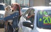 A woman waits with her puppy while her companion tries to get a bargain on a car. 