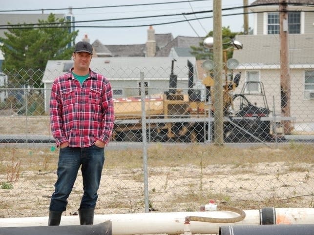 In 2014, Nick Honachefsky posed in front of the empty lot where his home once stood. Seven years after Superstorm Sandy and 5 years after the photo, he is still waiting for government approvals to rebuild. 