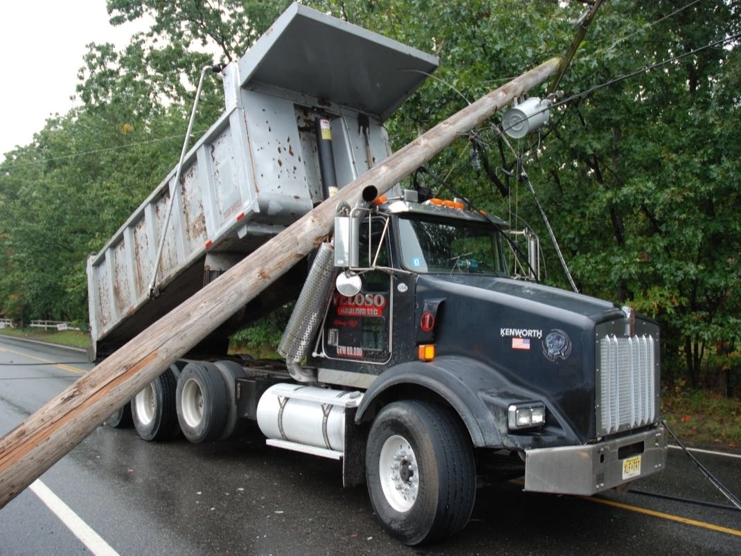 A dump truck snagged wires hanging across the road, snapping a utility pole and shutting down traffic for several hours Tuesday, Manchester police said. 