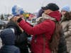 A Ukrainian teen tries on a hat as families pick up needed items at a border crossing in Poland, where refugees have come to flee the Russian invasion. 