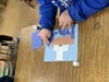 A child makes a ship out of pieces of paper for Columbus Day. 