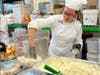 A student grabs marshmallows for sweet potatoes as more than 3,500 Thanksgiving meals are assembled at the OCVTS's Brick Center.  