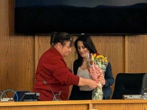 Roxanne Conniff receives flowers from Councilwoman Sandy Gravatt-Drake after announcing her resignation from the council on April 27.