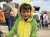 A delighted boy wearing a dinosaur costume attends the first-ever Trunk or Treat with the Library and Village.