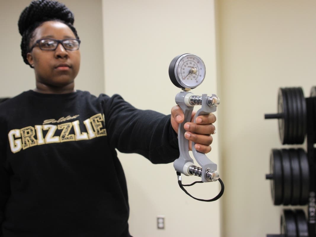 OU student Artishia Moore demonstrates the use of a handgrip dynamometer, a device that measures grip strength