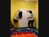 Volunteers add textured, padded wall decor to brighten the space