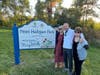 From left to right: Maureen Moutvic Sheetz, Peter Moutvic, and Mary Moutvic pose next to the Moutvic Family StoryWalk® sign.