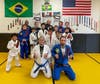 Christian Defiris, back row center, gathers with his students and instructors in his new gym’s Brazilian jiu jitsu, wrestling and judo room. 
