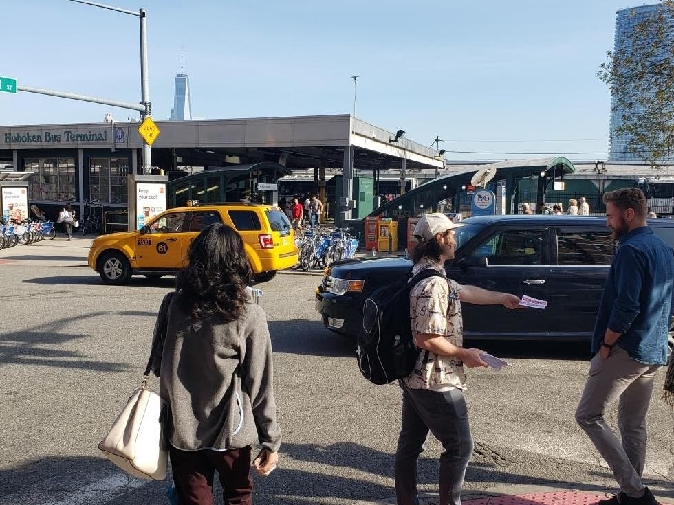 An activist hands out a flyer supporting a “millionaire tax” in New Jersey at Hoboken Terminal on May 9, 2019.
