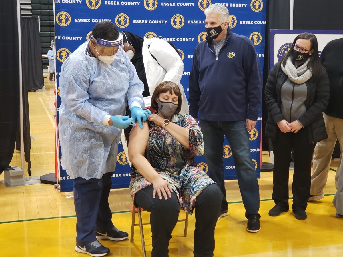 Essex County Executive Joseph DiVincenzo Jr. (right) looks on as Bloomfield resident Bonnie Rogers (seated), a school nurse at the Essex County West Caldwell School of Technology, receives her second dose of the Moderna vaccine on Jan. 23.