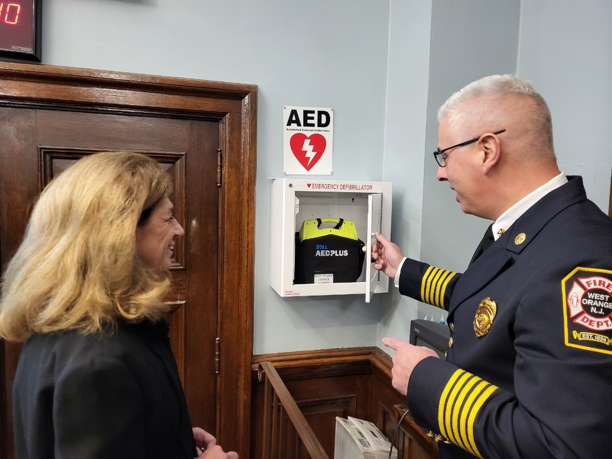 Mayor Susan McCartney listens as West Orange Fire Chief Anthony Vecchio explains the lifesaving capabilities typical of the automated external defibrillator located in the council chambers.