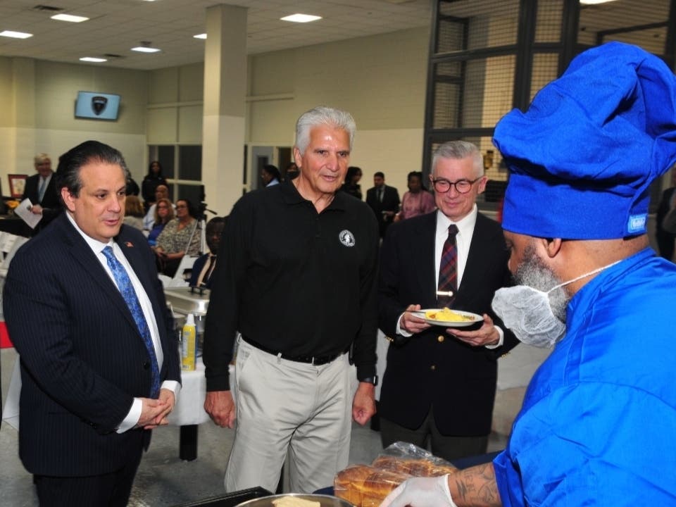 Essex County officials look on as an inmate who is enrolled in a food service certification course at the Essex County Correctional Facility prepares an omelet at a press conference on May 8.