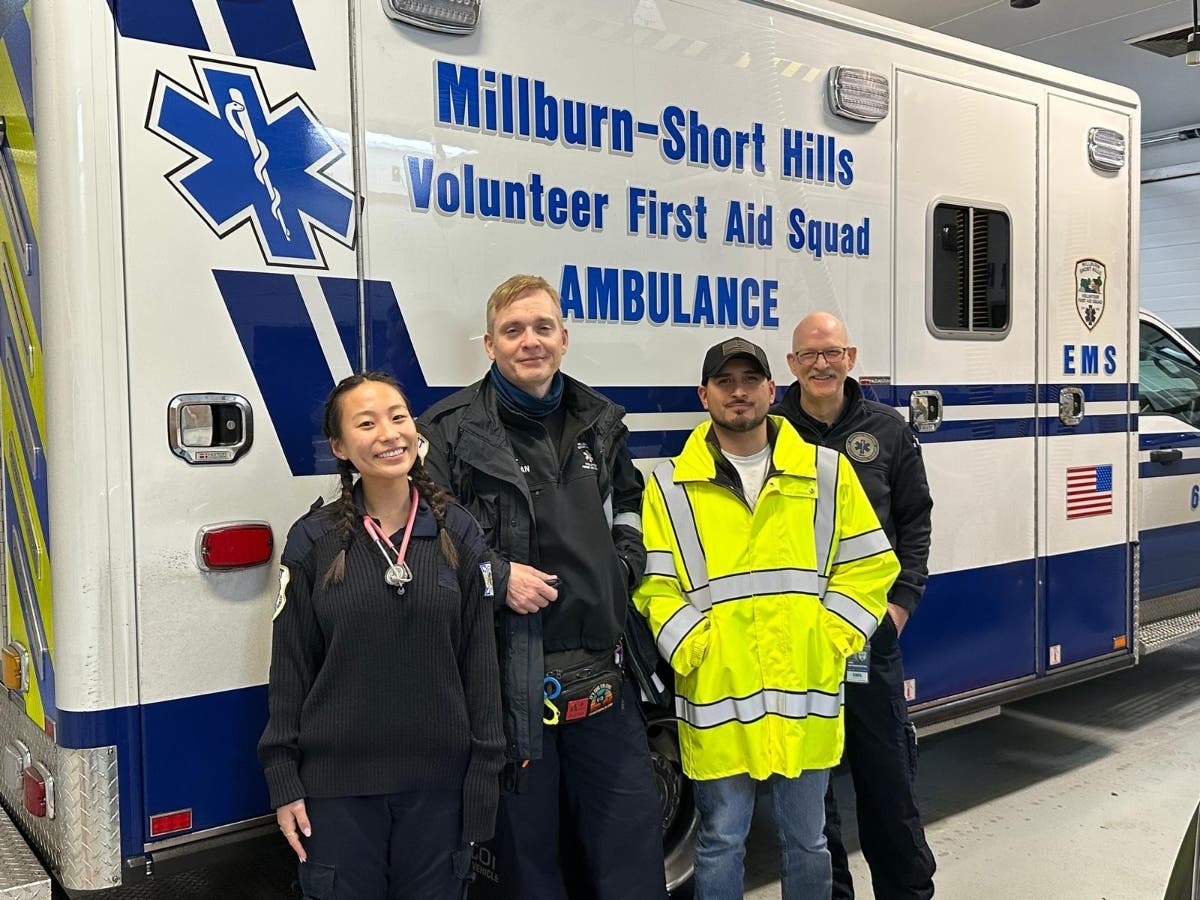 Four members of the Millburn-Short Hills Volunteer First Aid Squad stand in front of an ambulance at the squad's station in Millburn, N.J. Left to right, EMT Hannah Ma, squad Captain Kevin Ryan, Crew Chiefs Wilson Cabrera and Jon Hetherington.
