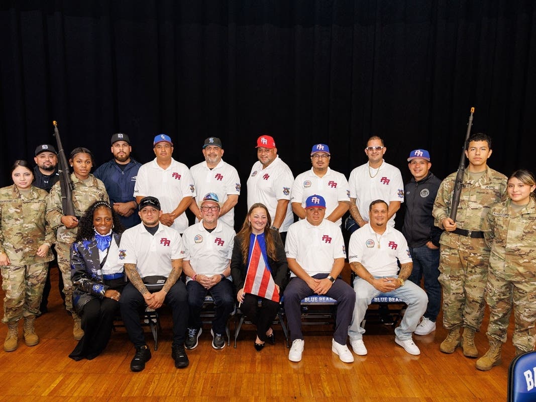Principal Natasha Pared, center front, and Board Member Louis Maisonave, Jr., standing third from right, pose with nine police officer from Puerto Rico, members of the Barringer High School Junior ROTC program, and Barringer High School staff.