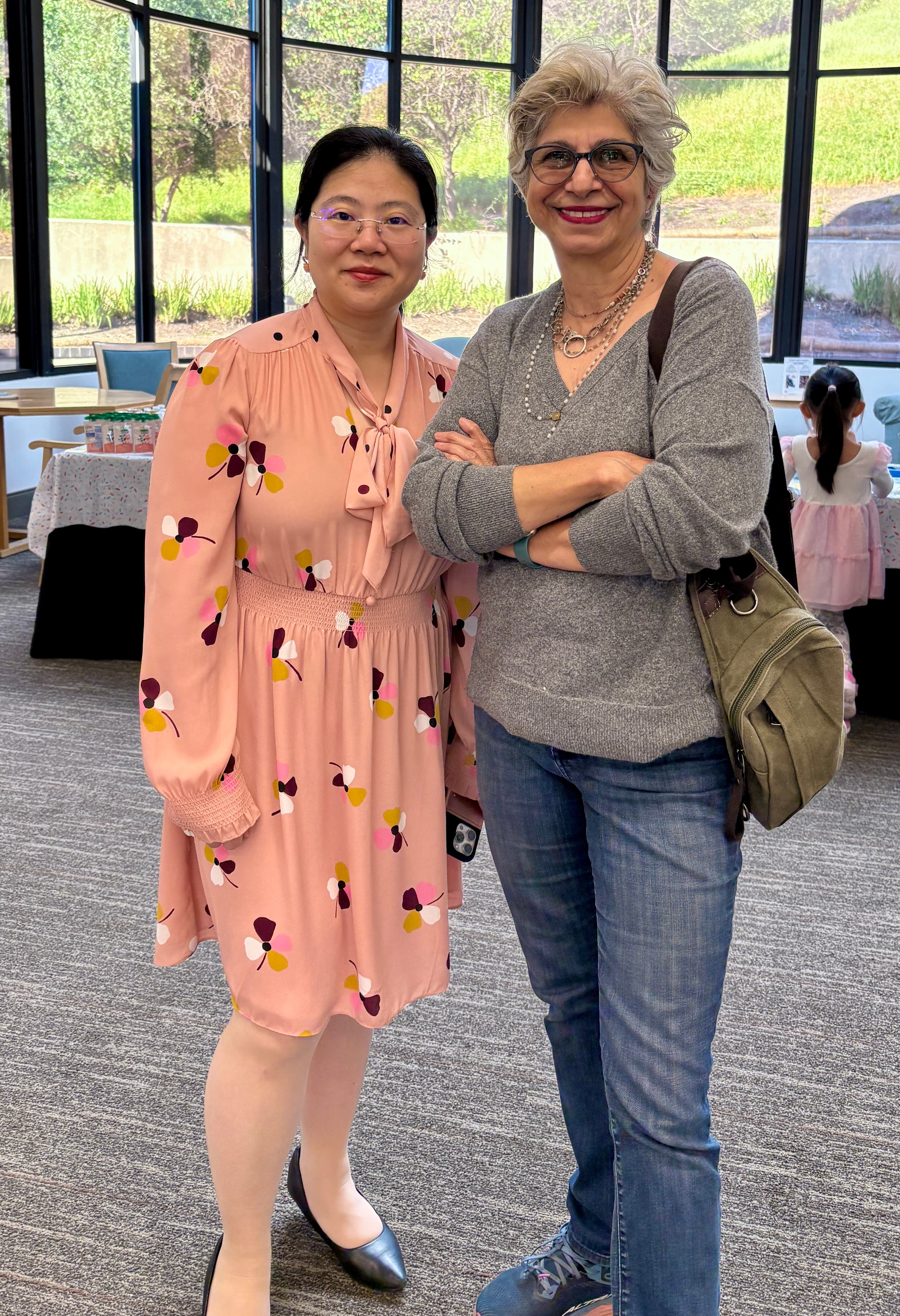 Two women pose side by side in front of the bay window at Alcosta Senior and Community Center