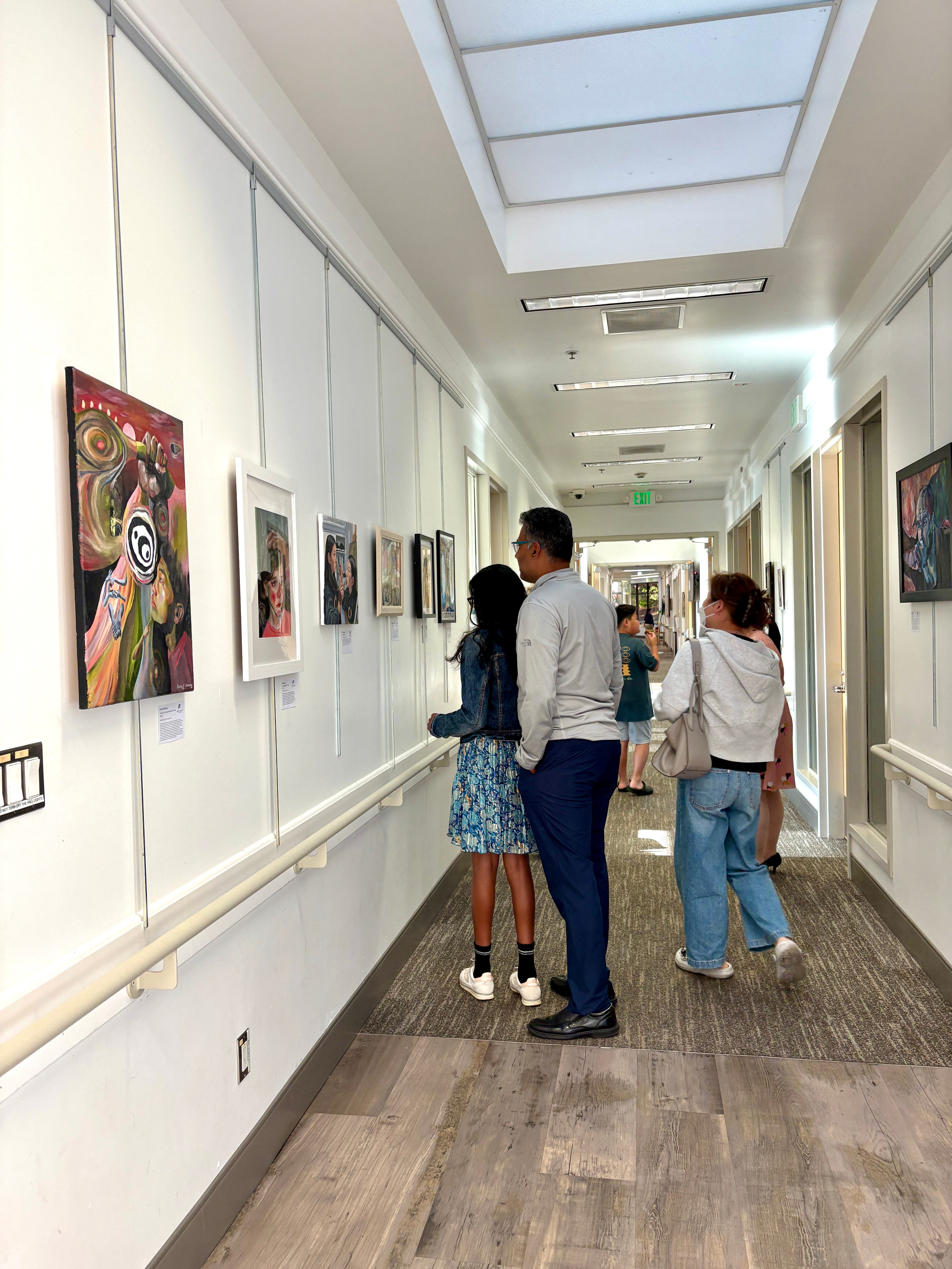 People of various ages viewing an art show in a corridor