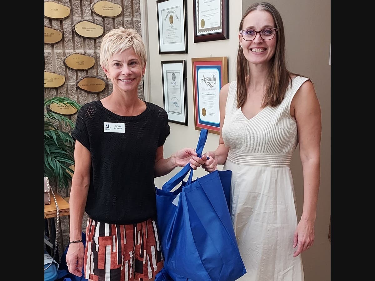 Assistance League Diablo Valley’s Operation School Bell and Common Threads member volunteer Jamie Peters (l) hands a bag of clothing for Common Threads identified high school students to Rosie Reid (r), HOPE Program Specialist, MDUSD.