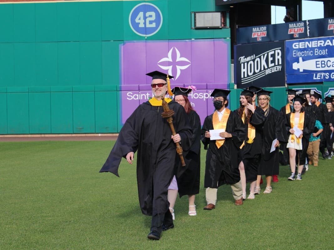 Dr. Eric Mosher, leading graduates on to the field at Dunkin Park in Hartford, served as the faculty Marshal for Asnuntuck Community College’s 50th Commencement ceremony on May 25. 