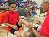 A Back to School Shop volunteer helps a young shopper tie his new pair of sneakers during the 2019 event.