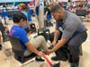State Representative Hubert Delany helps a young shopper find cool shoes at the 2024 Back to School Shop.