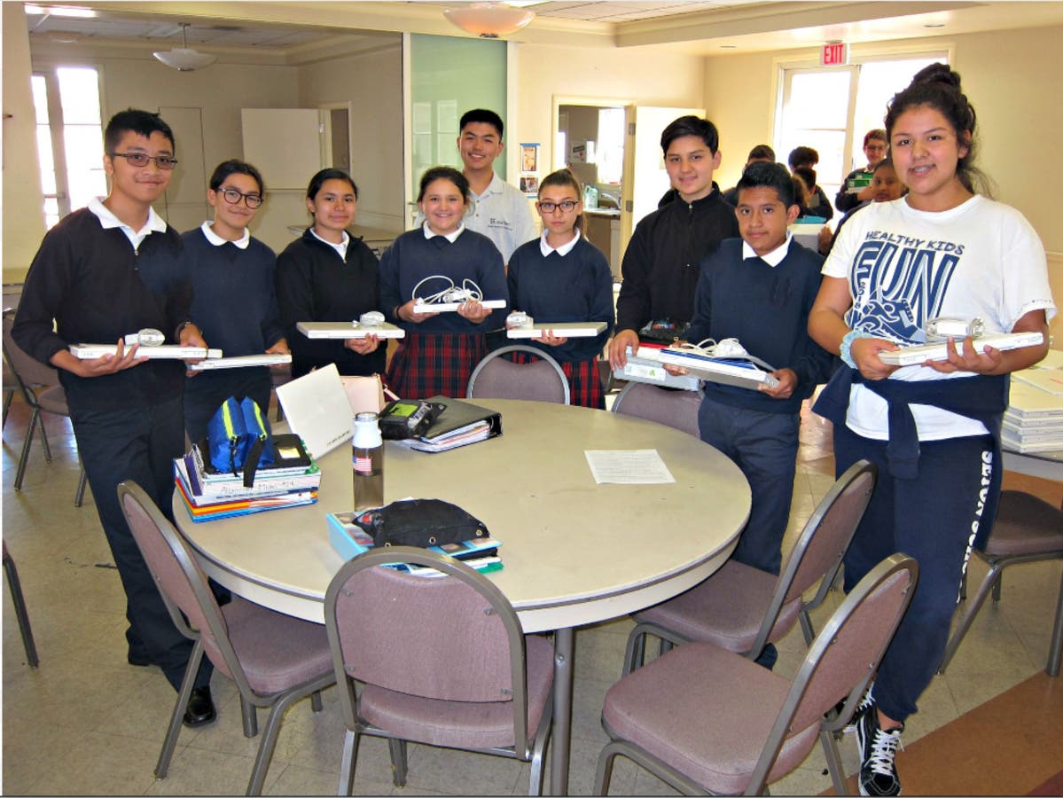 Students standing in a circle were thrilled with their new laptops with Kevin Gao, EqOpTech President, standing in back