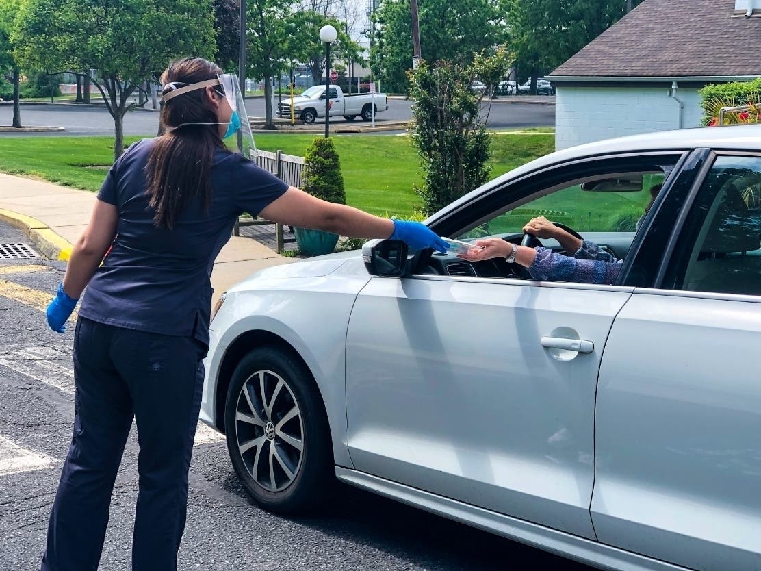 VNA Certified Medical Assistant Ali Robles provides a COVID-19 test kit to a local resident at the Red Bank Family YMCA, now a site for testing three days a week by the Visiting Nurse Association of Central Jersey Community Health Center.