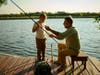 Grandfather teaching grandson how to fish on a lake