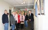 Members and guests of the Digital Photography Club of Annapolis pose by some of their work during the artists’ reception