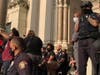 A Jersey City police officer kneels on the steps of City Hall.