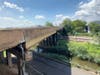 The man was hanging onto the fence over the railroad tracks on this bridge.