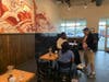 A customer chats with LeGrand in the shop Monday, with a unique mural of the Middletown area on the wall above them.