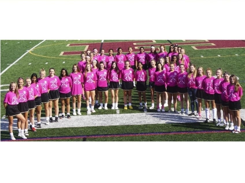 Varsity and Junior Varsity Teams are shown in the shape of the beat cancer logo at the HHS stadium with their coaches.